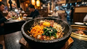 Close-up detalhado de um Bibimbap em tigela de pedra aquecida, destacando as cores vibrantes dos vegetais e a gema de ovo central em ambiente de restaurante japonês refinado
