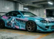 Carro esportivo japonês modificado em estacionamento subterrâneo exibindo arte em vinil de estilo anime fluindo com as linhas aerodinâmicas da carroceria, exemplificando a cultura Itasha de design.